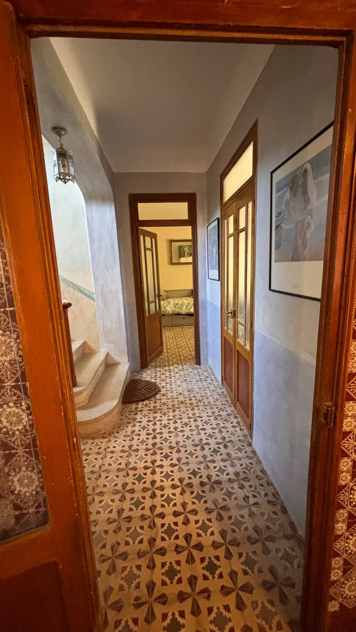 Pasillo interior con suelo de mosaico hidráulico original, puertas de madera y farol antiguo